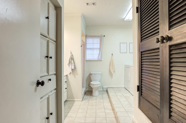 bathroom featuring washer / clothes dryer, tile patterned flooring, vanity, toilet, and a textured ceiling