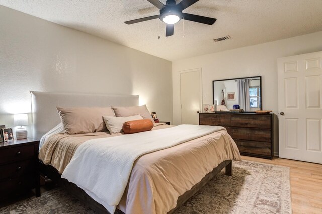 bedroom with ceiling fan, light hardwood / wood-style flooring, and a textured ceiling