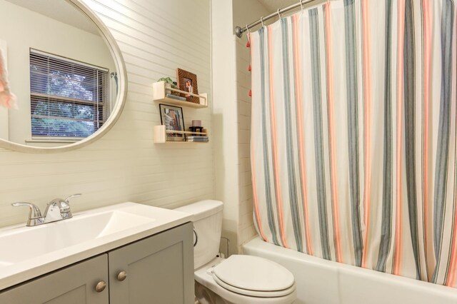 bathroom featuring vanity, wood walls, and toilet