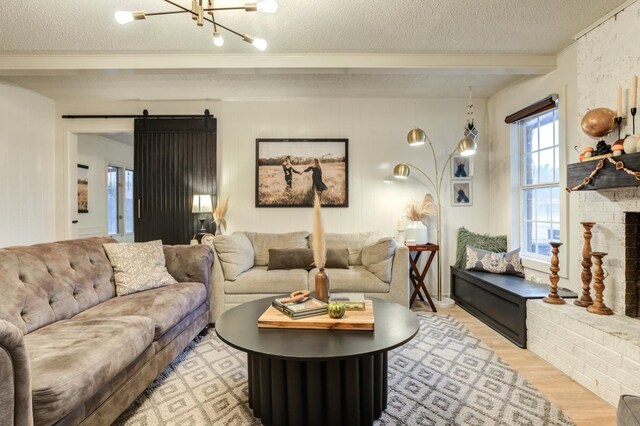 living room featuring a fireplace, a barn door, light hardwood / wood-style floors, and a textured ceiling