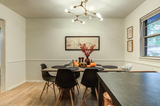 dining area featuring hardwood / wood-style floors, a textured ceiling, and a notable chandelier