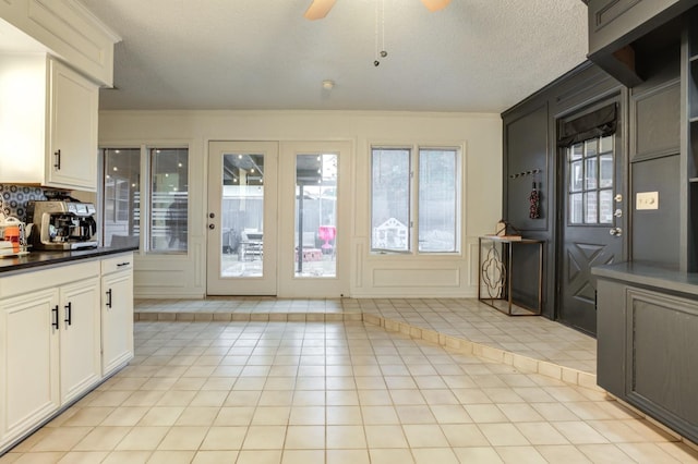 doorway with ornamental molding, a textured ceiling, and light tile patterned floors