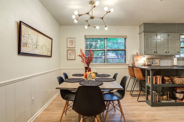 dining space featuring a notable chandelier, light hardwood / wood-style floors, and a textured ceiling