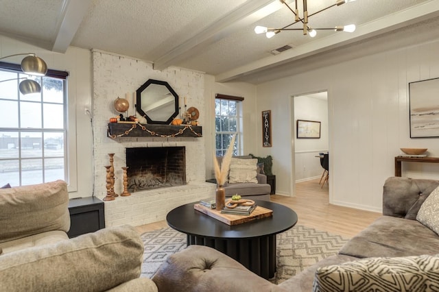 living room with beam ceiling, a fireplace, a healthy amount of sunlight, and light wood-type flooring