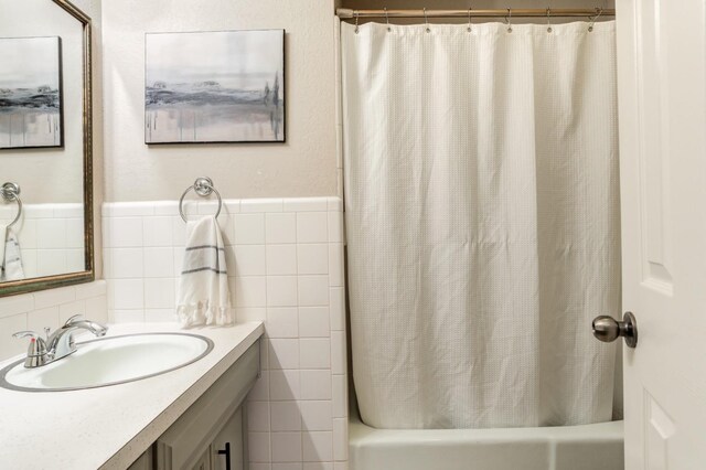 bathroom featuring vanity, tile walls, and shower / bathtub combination with curtain