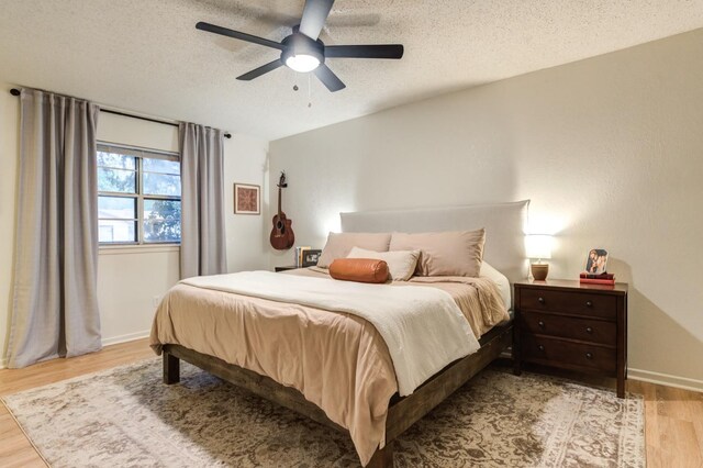 bedroom with ceiling fan, light hardwood / wood-style floors, and a textured ceiling