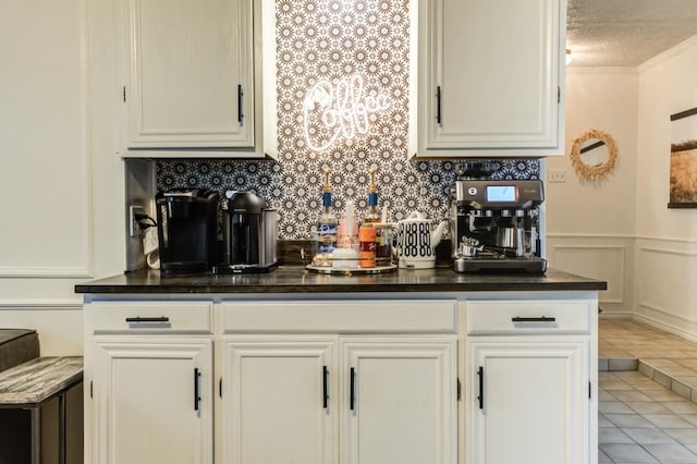 kitchen with white cabinetry, ornamental molding, light tile patterned floors, and a textured ceiling