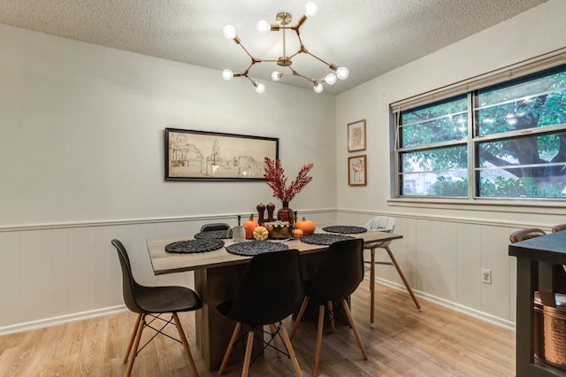 dining room with light hardwood / wood-style flooring, a chandelier, and a textured ceiling