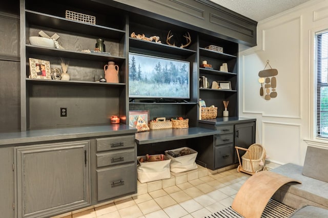 bar featuring gray cabinets, light tile patterned flooring, built in desk, and a textured ceiling