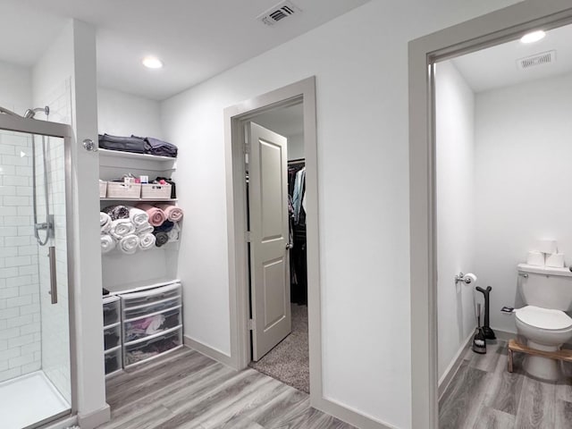 interior space featuring hardwood / wood-style flooring, toilet, and walk in shower