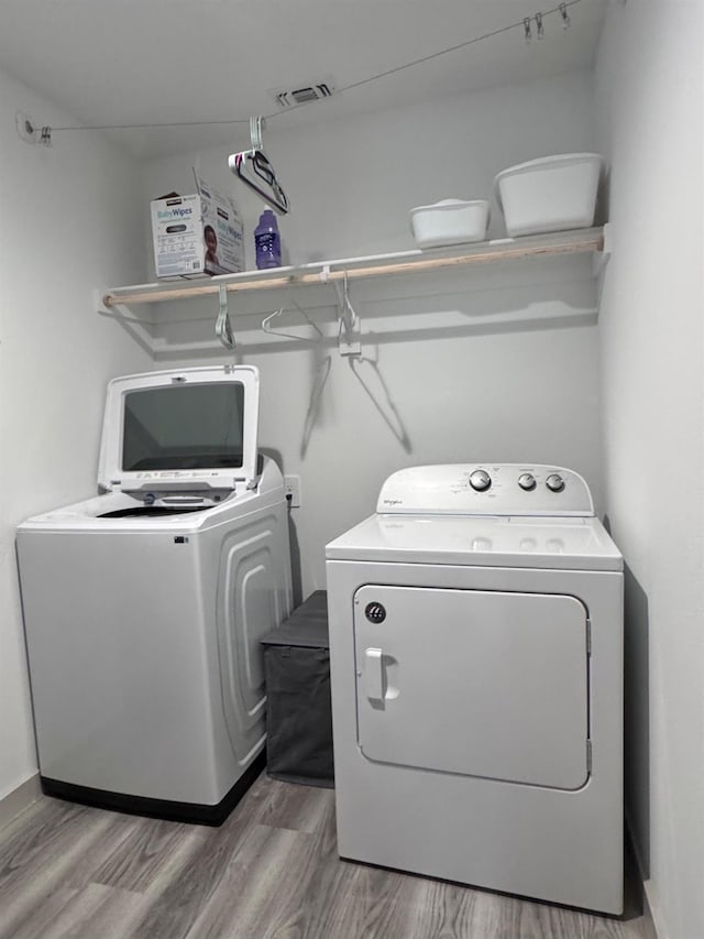 laundry area with wood-type flooring and separate washer and dryer