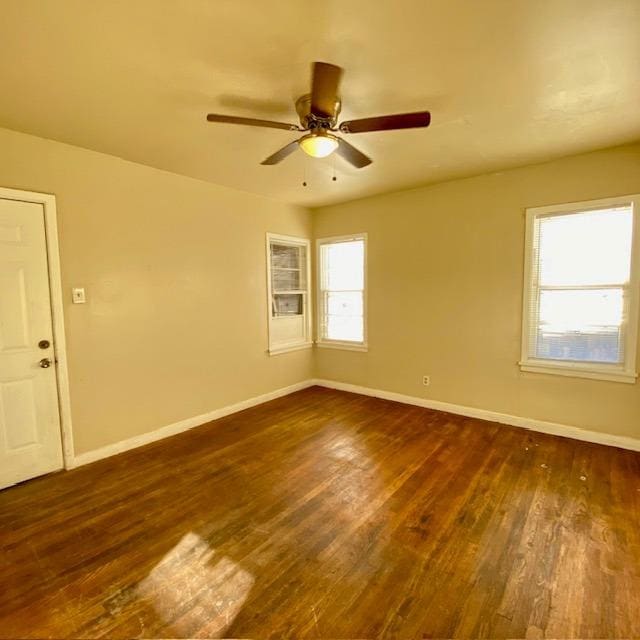 empty room featuring ceiling fan, plenty of natural light, and dark hardwood / wood-style floors