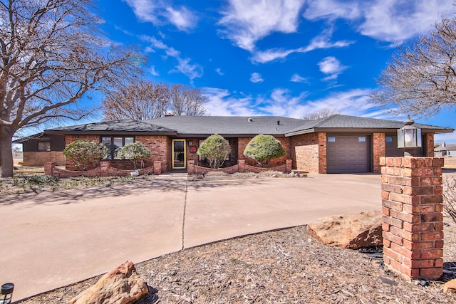 ranch-style house featuring driveway, a shingled roof, an attached garage, and brick siding