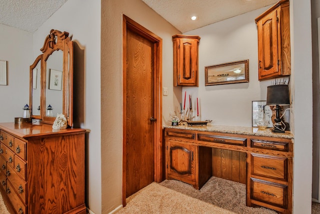 hallway with a textured ceiling and light carpet