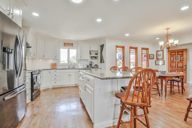 kitchen featuring a sink, stainless steel fridge, a kitchen breakfast bar, electric range oven, and white cabinetry