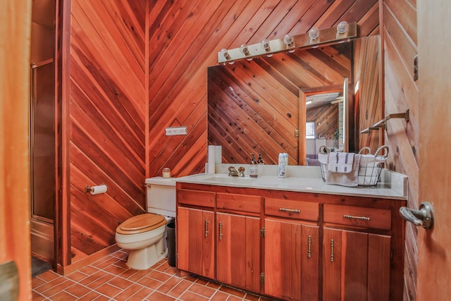 bathroom featuring toilet, tile patterned flooring, wood walls, and vanity