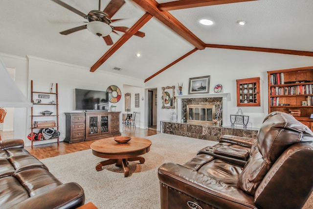living room featuring a premium fireplace, lofted ceiling with beams, a ceiling fan, visible vents, and wood finished floors