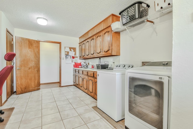 clothes washing area with light tile patterned floors, separate washer and dryer, cabinet space, and a textured ceiling