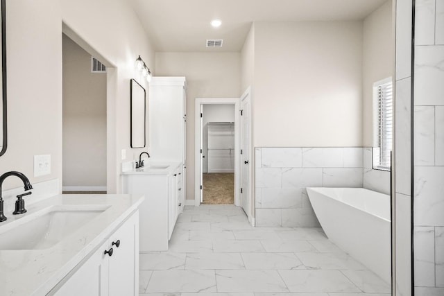 bathroom with vanity, tile walls, and a bathing tub