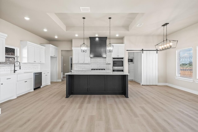 kitchen featuring a tray ceiling, decorative light fixtures, a barn door, and a kitchen island