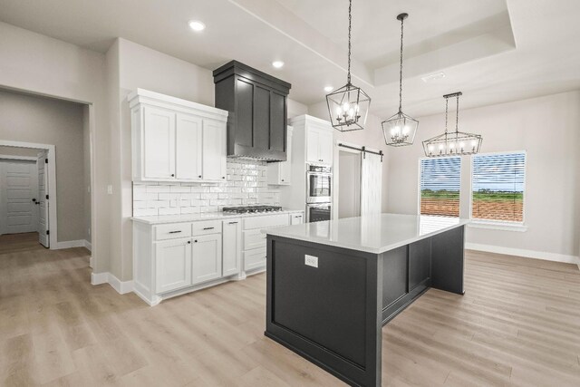 kitchen featuring white cabinetry, appliances with stainless steel finishes, a kitchen island, pendant lighting, and a barn door