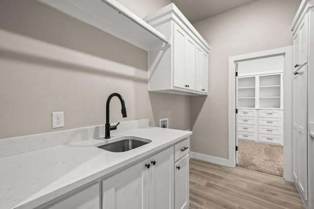 laundry area with cabinets, sink, washer hookup, and light wood-type flooring