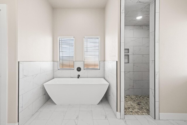 bathroom featuring shower with separate bathtub and tile walls