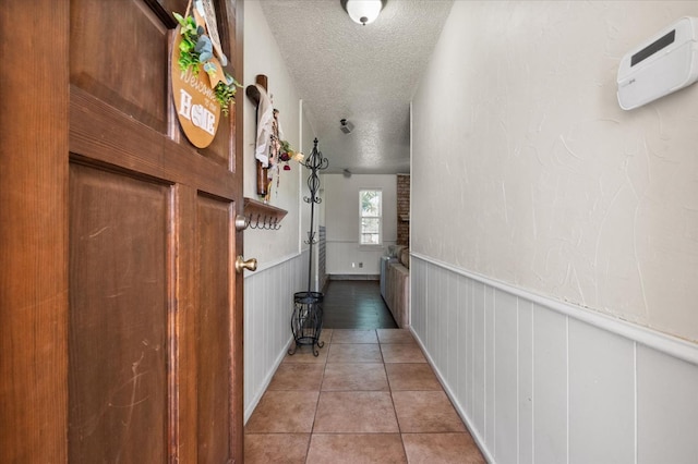 corridor featuring a textured ceiling and light tile patterned flooring