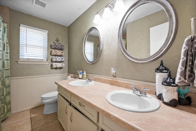 bathroom featuring tile patterned flooring, vanity, a textured ceiling, and toilet