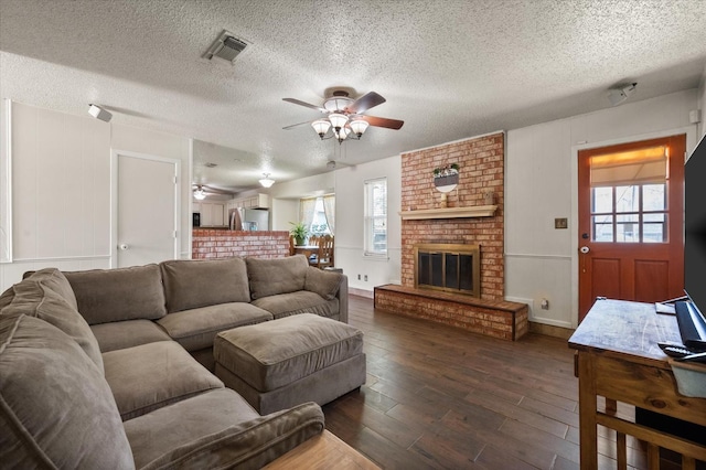 living room featuring a healthy amount of sunlight, a brick fireplace, dark hardwood / wood-style floors, and ceiling fan