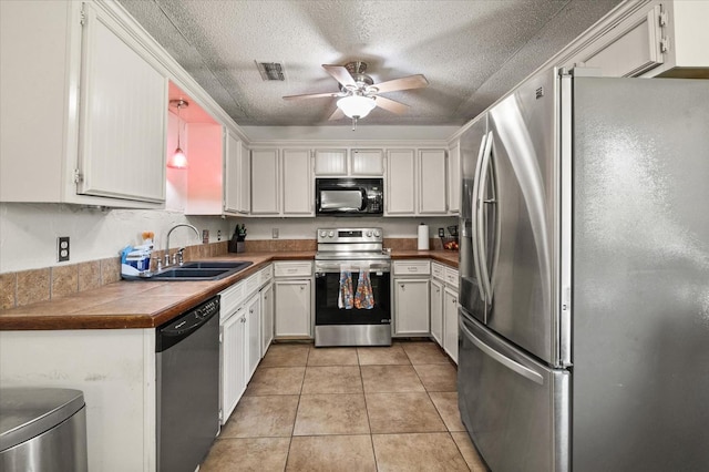 kitchen featuring light tile patterned flooring, appliances with stainless steel finishes, tile countertops, decorative light fixtures, and sink