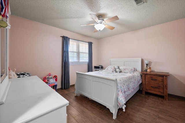 bedroom featuring dark wood-type flooring, a textured ceiling, and ceiling fan