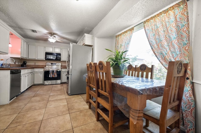 kitchen featuring light tile patterned flooring, sink, ceiling fan, stainless steel appliances, and white cabinets