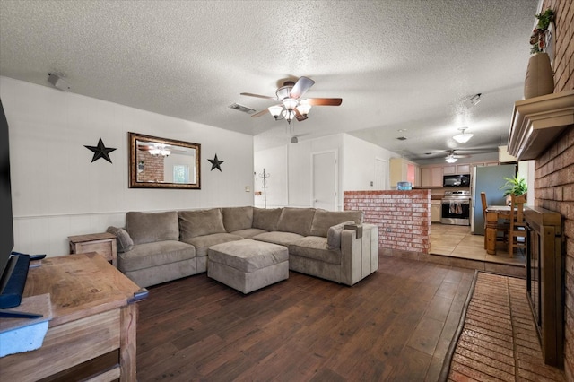 living room featuring hardwood / wood-style flooring, ceiling fan, and a textured ceiling