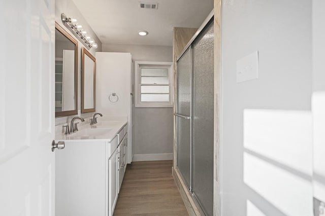 5217 45th St, Lubbock, TX 79414 - bathroom featuring a stall shower, double vanity, wood finished floors, and baseboards