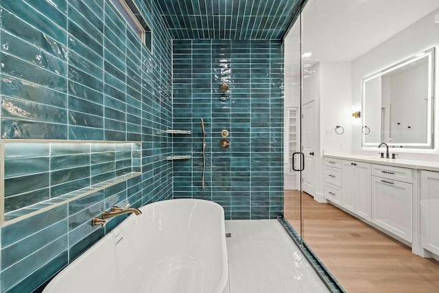 bathroom featuring tile walls, vanity, wood-type flooring, and plus walk in shower