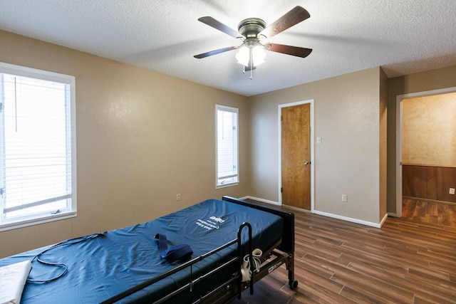 bedroom with multiple windows, dark wood-type flooring, and a textured ceiling