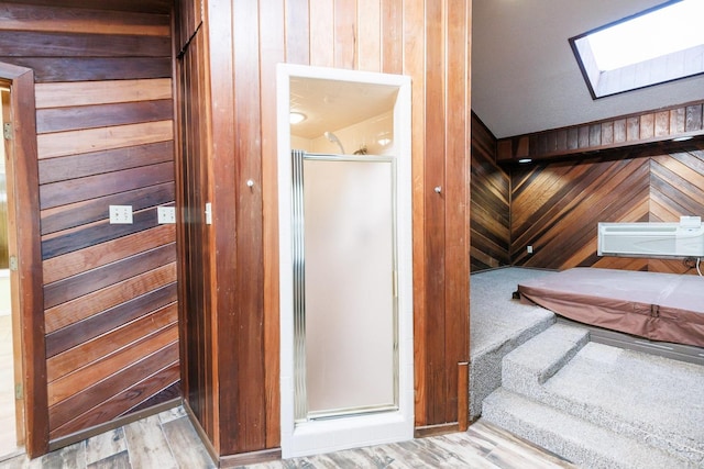 interior space featuring a skylight, hardwood / wood-style flooring, a wall mounted air conditioner, and wood walls