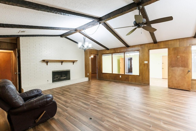 living room with vaulted ceiling with beams, a brick fireplace, a textured ceiling, wooden walls, and hardwood / wood-style floors