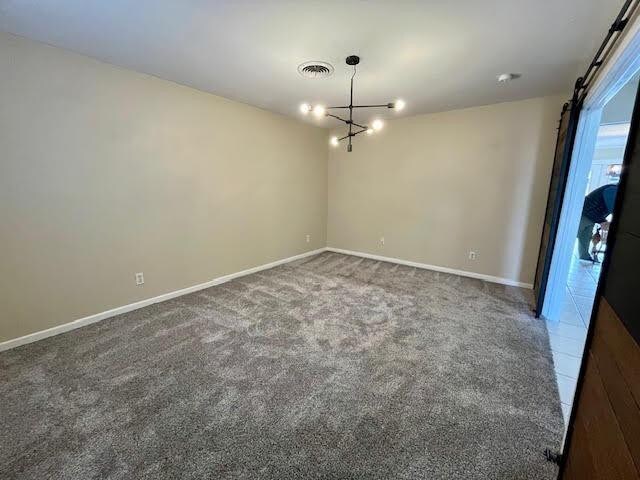 carpeted spare room with an inviting chandelier