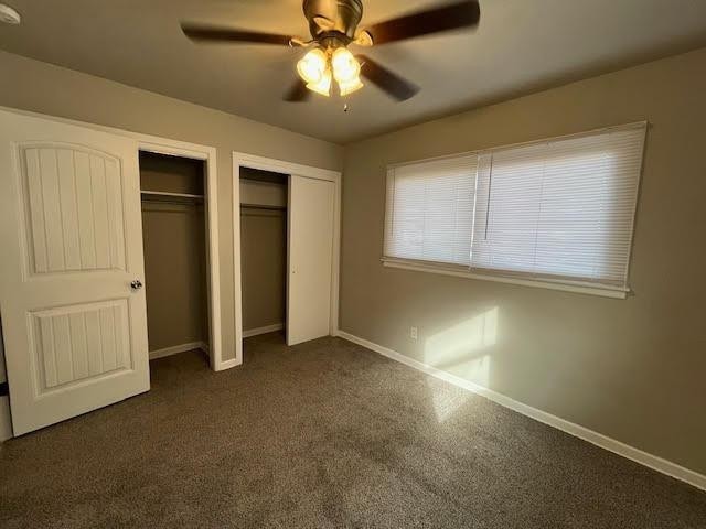 unfurnished bedroom with two closets and ceiling fan