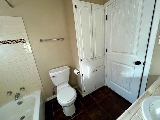 full bathroom with tile patterned flooring, sink, tiled shower / bath combo, and toilet