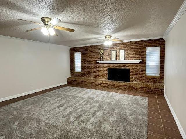 unfurnished living room featuring brick wall, a fireplace, dark tile patterned flooring, ornamental molding, and a textured ceiling