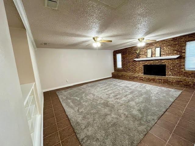 unfurnished living room with ceiling fan, brick wall, and a fireplace