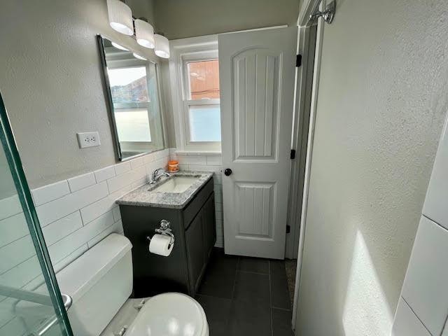 bathroom with tile patterned floors, vanity, toilet, and tile walls