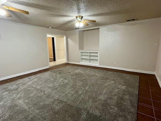 spare room featuring ceiling fan, a textured ceiling, and dark colored carpet