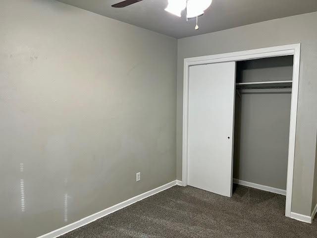 unfurnished bedroom featuring a closet, ceiling fan, and dark colored carpet