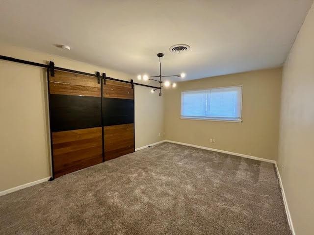 unfurnished bedroom featuring a barn door and dark colored carpet