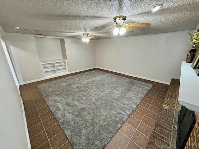 unfurnished room featuring a textured ceiling, ceiling fan, and dark tile patterned flooring