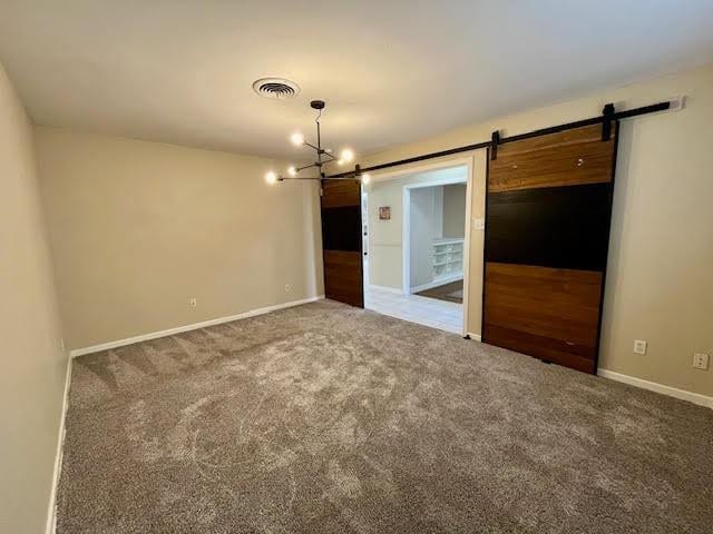 empty room featuring a barn door and carpet floors